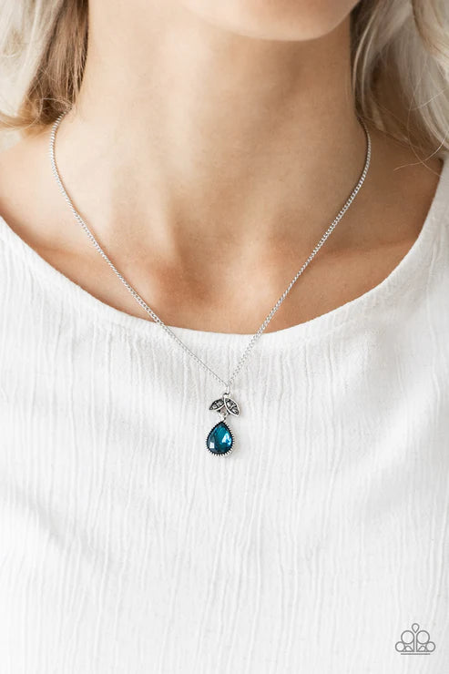 Necklace with a blue teardrop pendant worn by a person on a white background