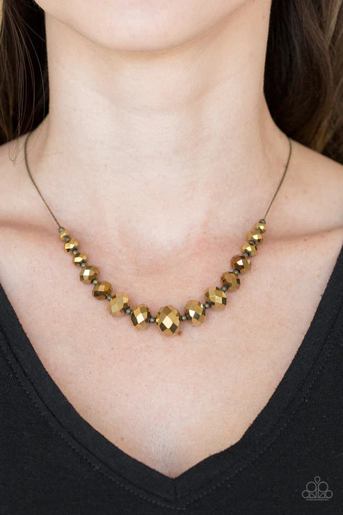 Necklace with gold beads worn by a person against a black background