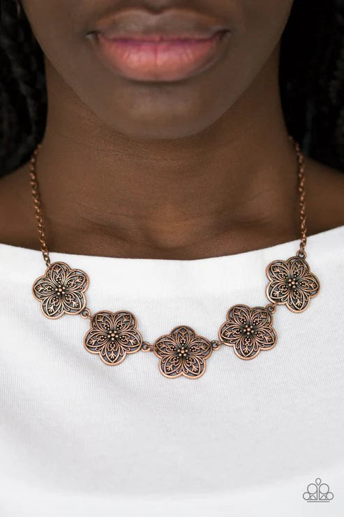 Necklace with floral designs worn by a person on a white background
