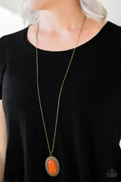 Long necklace with an orange pendant on a black background