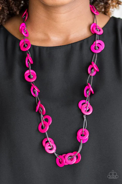 Necklace with pink circular links worn by a person against a black background