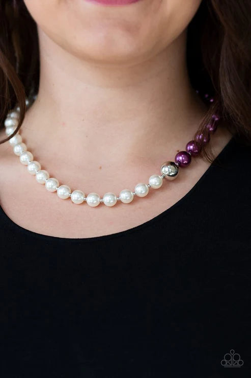 Pearl necklace with purple and silver beads worn by a person against a black background