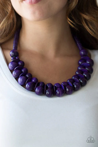 Purple beaded necklace worn by a person on a white background