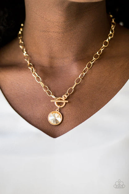 Gold necklace with a round pendant on a person wearing a white shirt