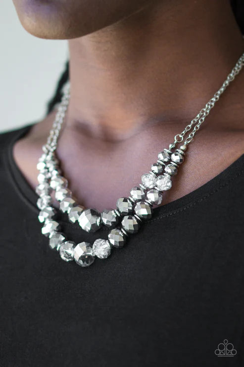 Necklace with faceted beads worn by a person against a black background
