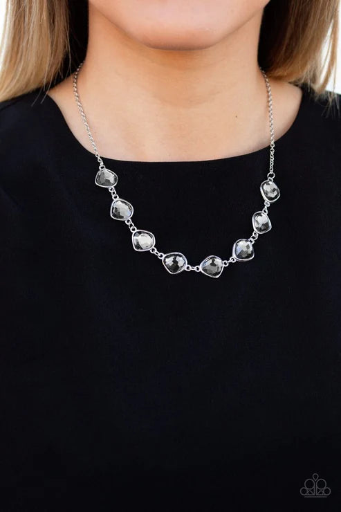 Silver necklace worn by a person against a black background