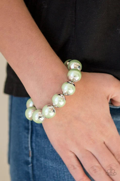 Light green beaded bracelet on a wrist with a black shirt and blue jeans in the background