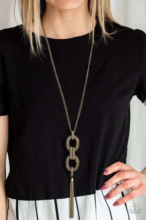 Person wearing a black top with a long gold necklace