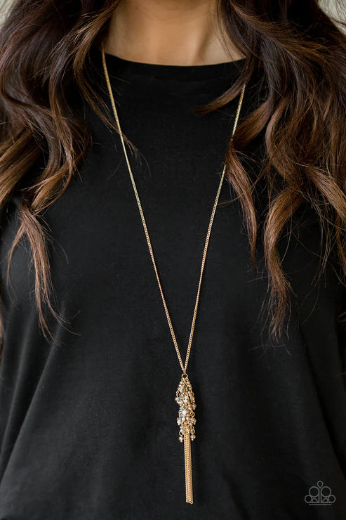 Long gold necklace with a decorative pendant on a black background