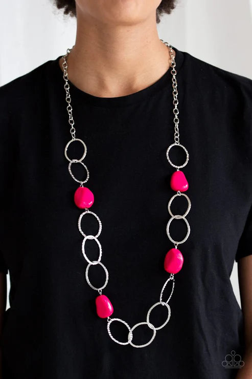 Necklace with pink beads and silver rings on a black shirt against a white background