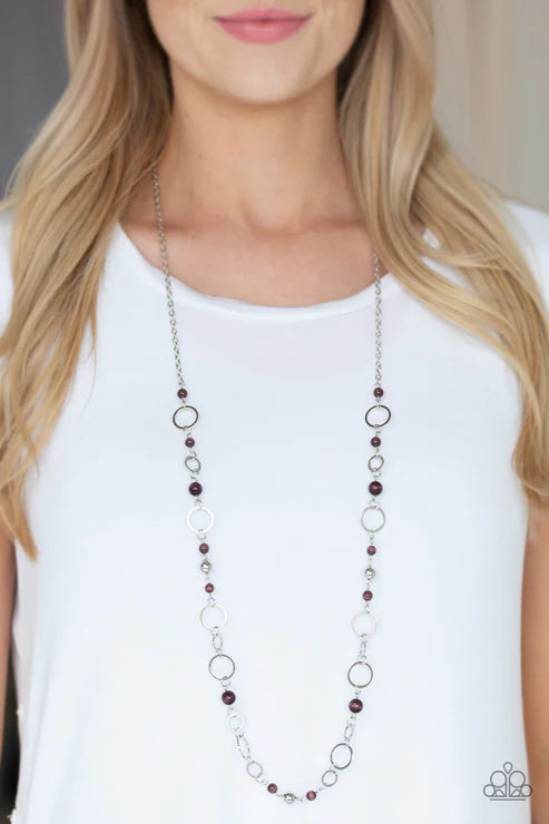 Woman wearing a long beaded necklace on a plain background