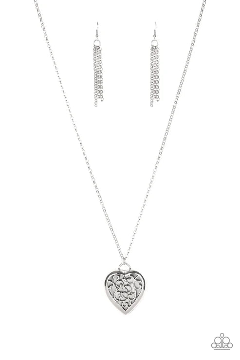 Silver heart-shaped pendant necklace and earrings on a white background