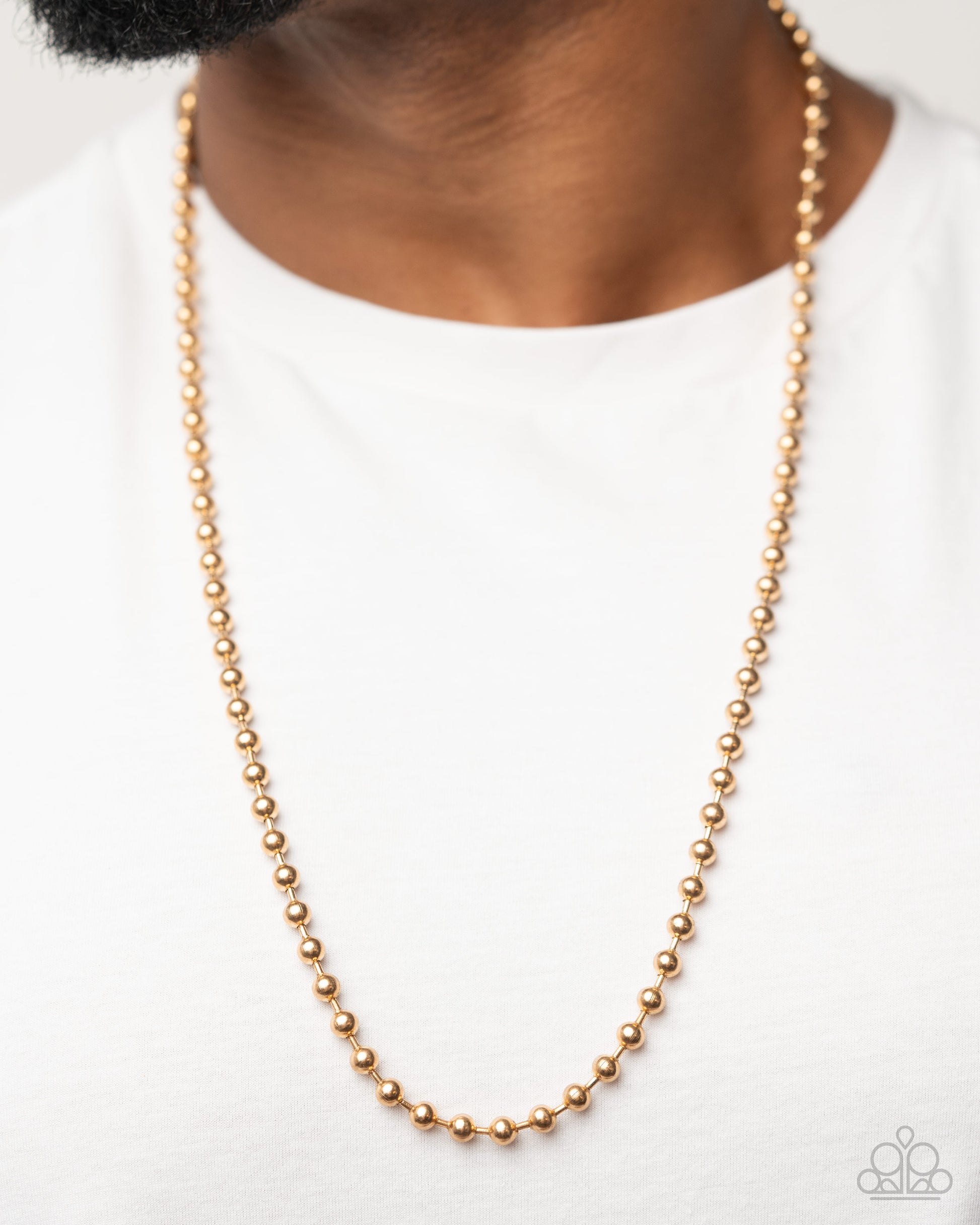 Gold beaded necklace worn by a person on a white background
