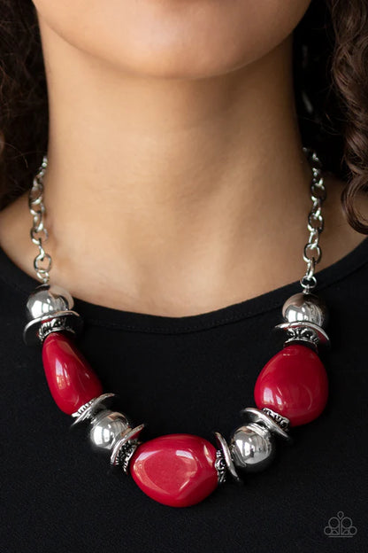 Necklace with red beads and silver accents on a black background
