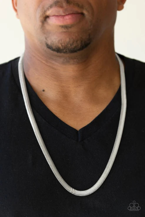 Man wearing a white necklace against a neutral background