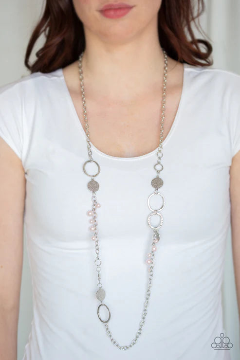 Long silver necklace worn by a person on a white background