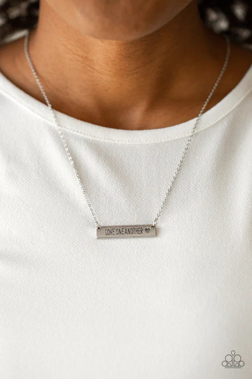 Silver necklace with engraved message on a white background