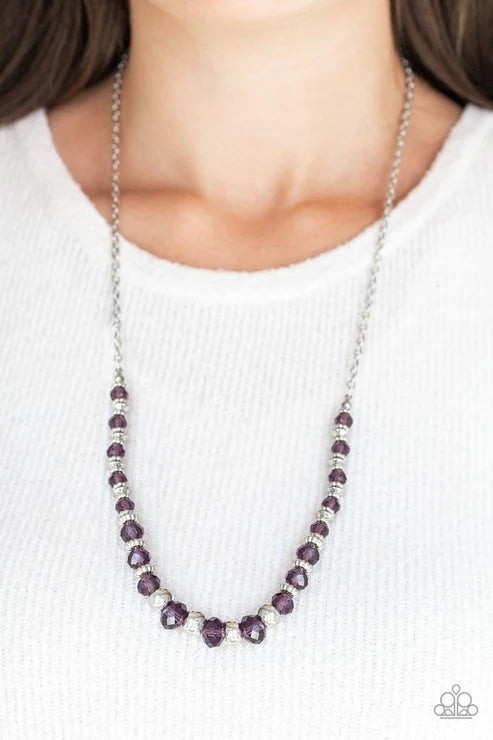 Necklace with purple beads worn by a person on a white background