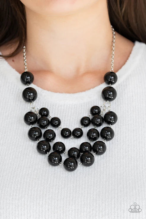 Black beaded necklace on a person wearing a white sweater