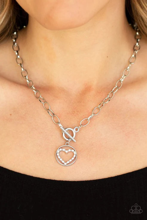 Silver chain necklace with a heart pendant worn by a person