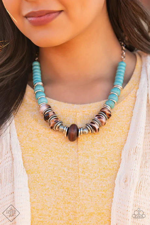 Necklace with turquoise, brown, and silver beads worn by a person in a yellow top.