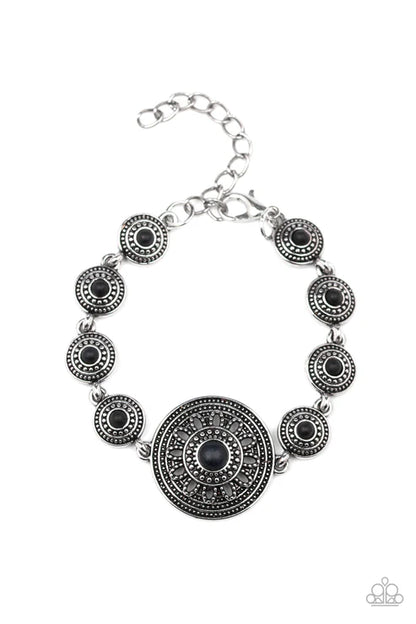 Silver bracelet with black circular stones on a white background