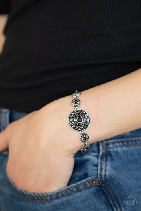 Silver bracelet on a wrist with a black background