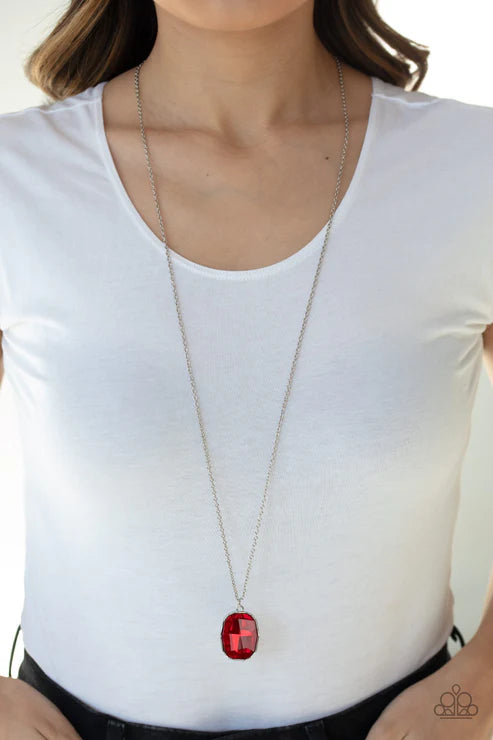 Person wearing a long necklace with a red pendant on a white background
