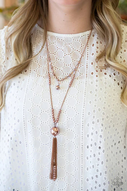 Layered necklaces with a tassel detail on a white blouse