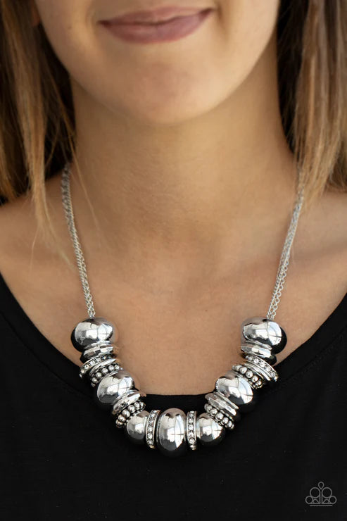 Silver beaded necklace worn by a person on a plain background