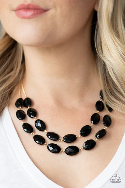 Black beaded necklace worn by a person with blonde hair.