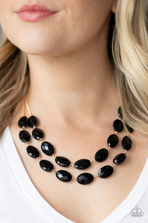 Black beaded necklace worn by a person with blonde hair.