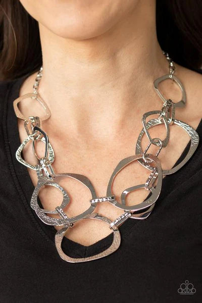 Silver chain necklace worn by a person against a black background