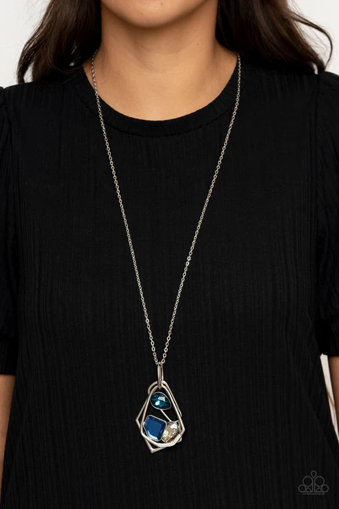 Person wearing a black top with a silver necklace featuring a blue gemstone pendant.