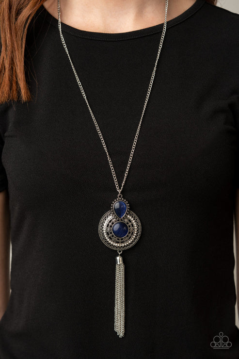Long necklace with blue stones and a tassel on a black shirt