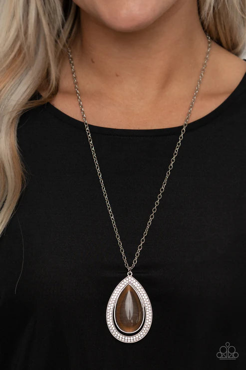 Necklace with a teardrop-shaped pendant worn by a person against a black background