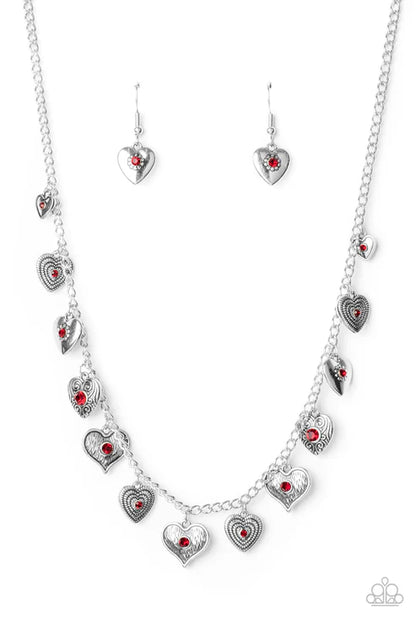 Silver heart-shaped jewelry set with red stones on a white background