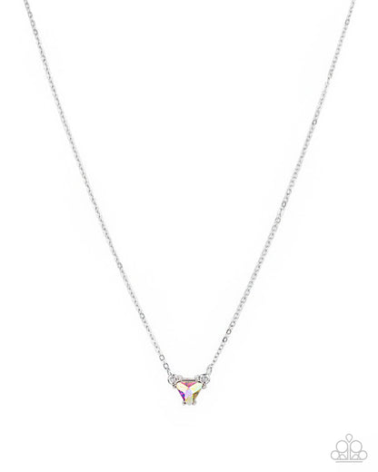 A silver chain necklace with a small triangular pendant featuring a clear faceted stone and tiny iridescent accents, shown on a plain white background. A small Paparazzi-style logo watermark appears in the bottom right corner.