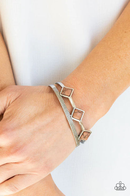 Silver bracelet with geometric design on a wrist against a white background