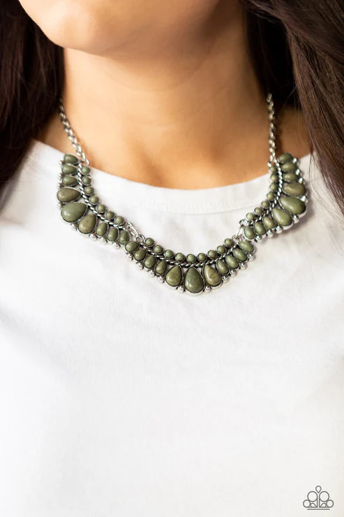 Necklace with green stones worn by a person on a white background