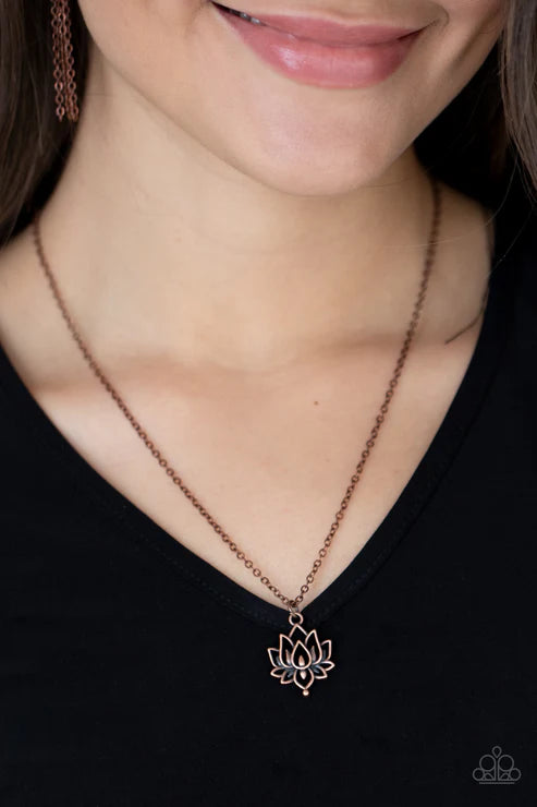 Necklace with a lotus flower pendant worn by a person against a black background