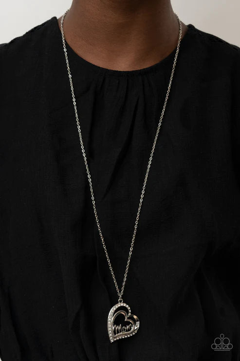 Long silver necklace with a heart pendant on a black background