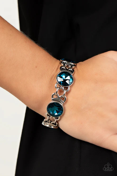 Silver bracelet with blue gemstones on a wrist against a black background