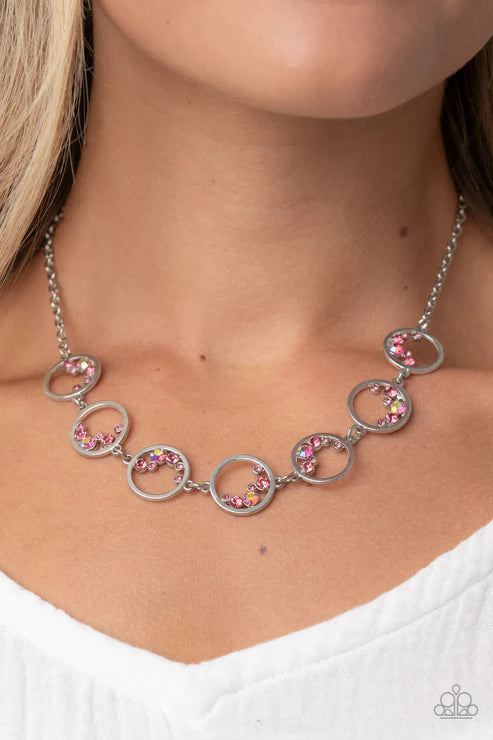 Necklace with circular links and pink gemstones worn by a person
