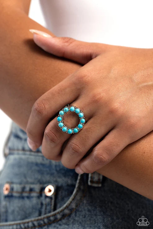 Turquoise beaded ring on a person's finger with a blurred background