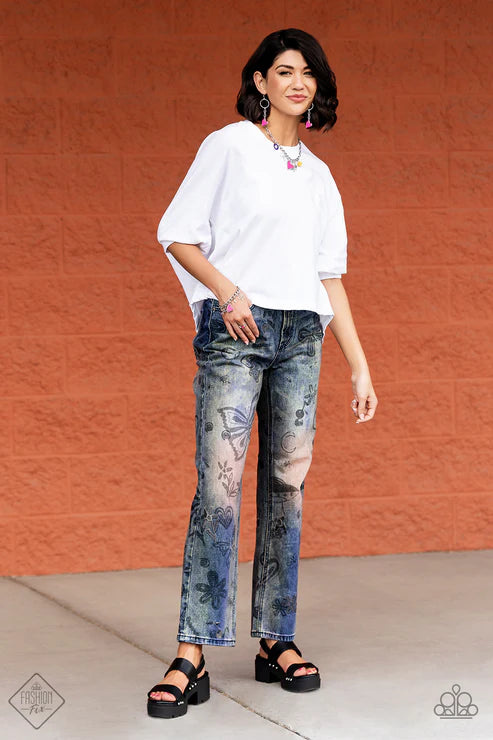 Woman wearing a white top and floral jeans against an orange wall.