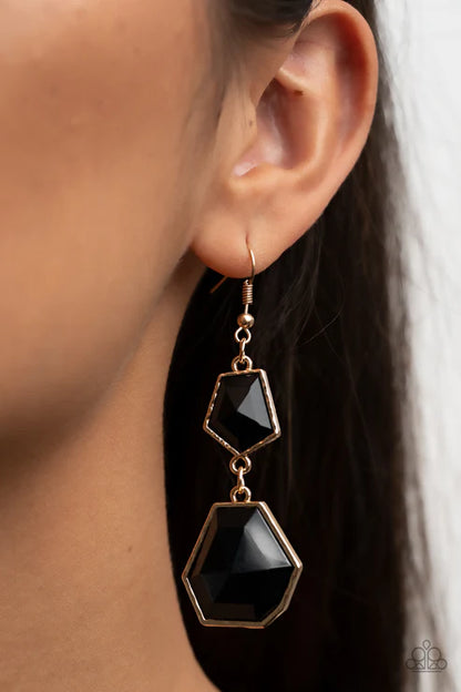 Close-up of an ear wearing a black earring with gold accents.