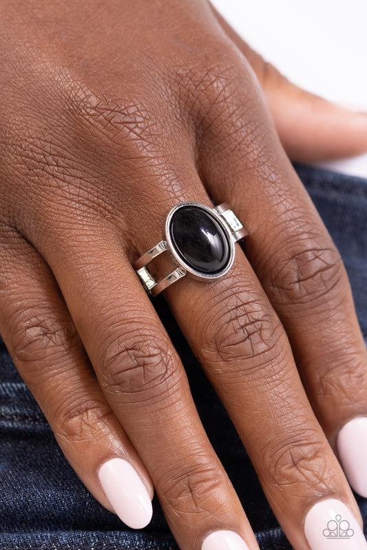 Close-up of a hand wearing a silver ring with a black stone on a white background