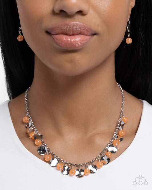 Necklace with orange and silver beads worn by a model on a white background