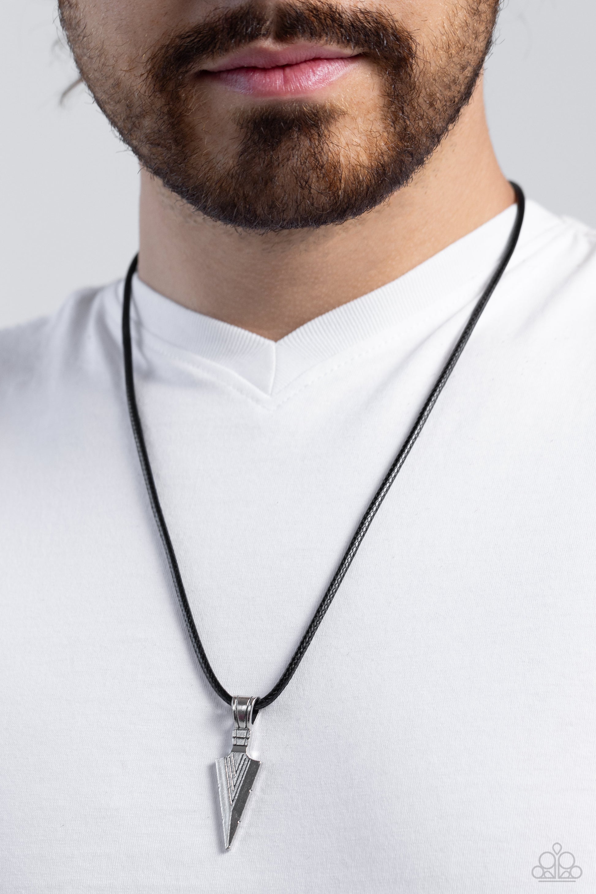 Man wearing a silver pendant necklace on a plain background